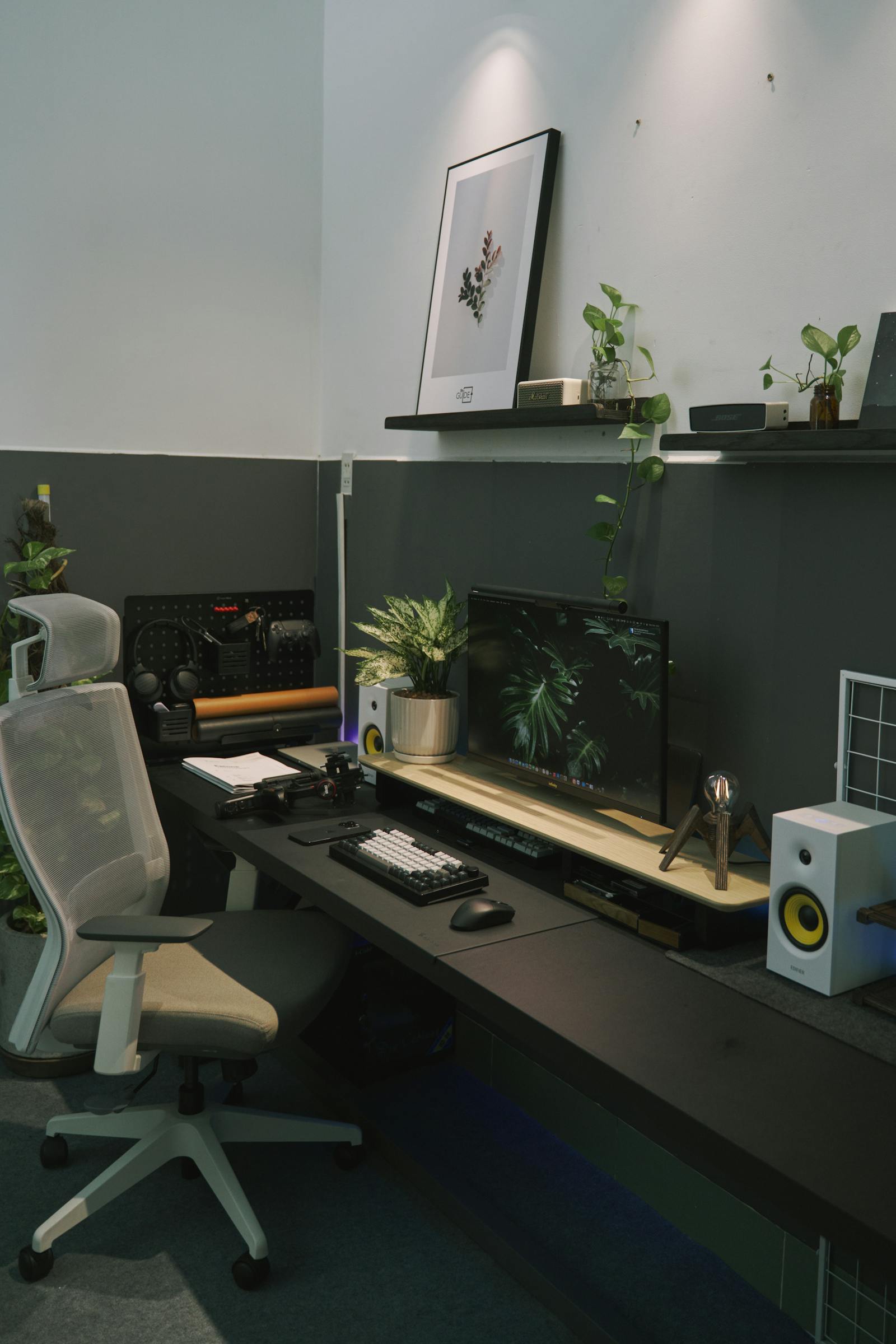 A desk setup with plants, laptop, and monitor